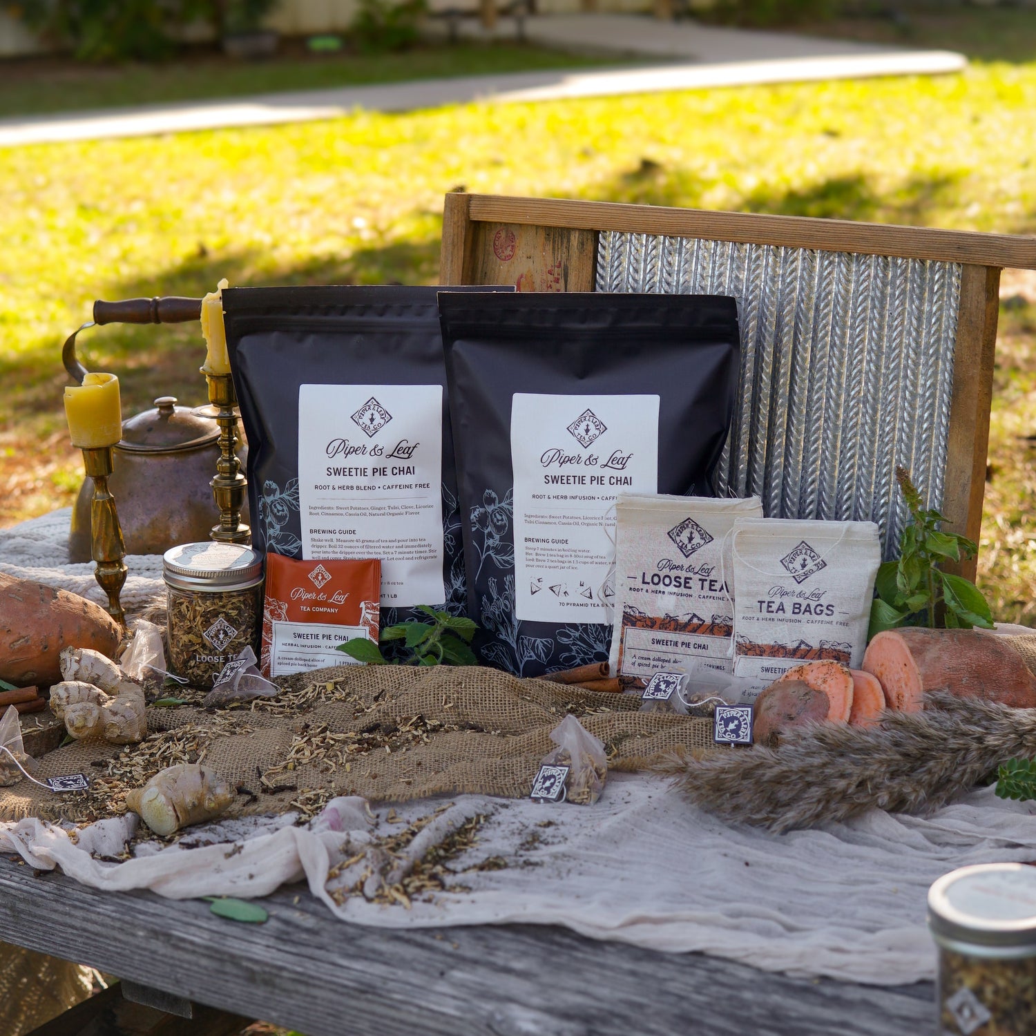 A cloth bag labeled "Loose Tea, Sweetie Pie Chai" sits on a wooden surface with dried citrus slices, sweet potatoes, and a cinnamon stick.