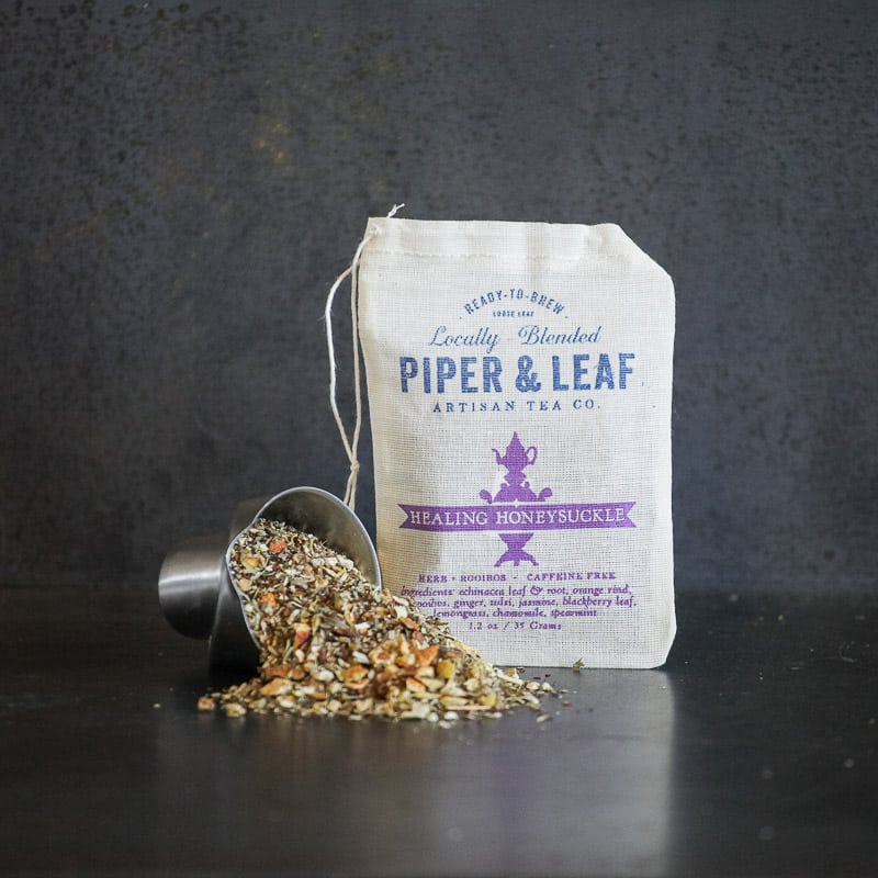 Metal measuring cup spilling loose leaf beside a muslin bag (Healing Honeysuckle)